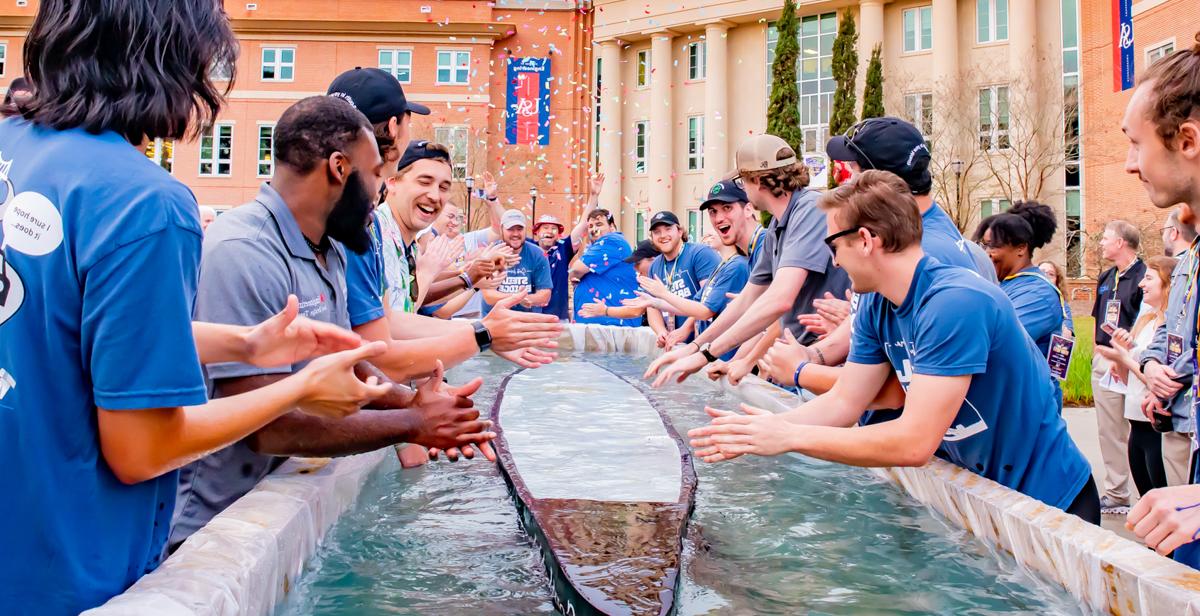 University of South Alabama College of Engineering students test the buoyancy of their 250-pound concrete canoe outside Shelby Hall. The group placed third in the competition on Dog River.  